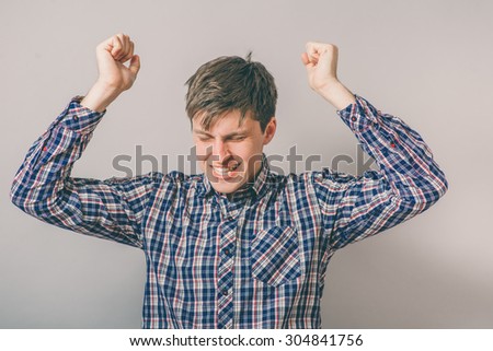 Handsome young man raising his arms in excitement
