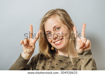 Happy smiling beautiful young woman showing two fingers or victory gesture