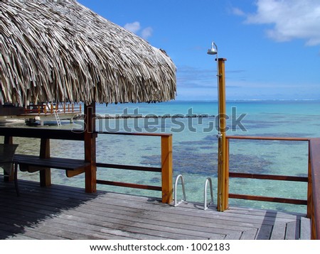 Over-water bungalow outside deck with outdoor shower, a ladder into the clear blue water and a view of the South Pacific.