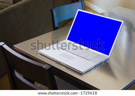 Apple Powerbook notebook computer with blue screen sitting on stainless steel kitchen table complete with clipping path around the screen. Blue screen & path will make easy to drop in own screenshots.