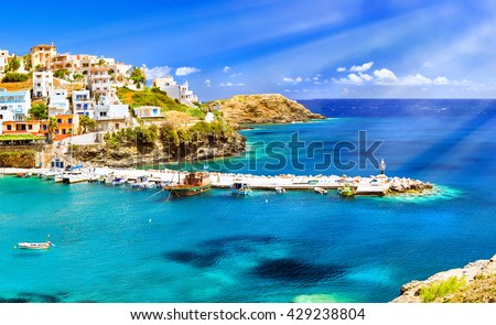 Harbour with marine vessels, boats and lighthouse. View from cliff on Bay with beach and architecture Bali - vacation destination resort, with clear turquoise ocean waters, Rethymno, Crete, Greece