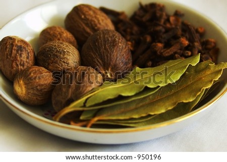 Dried nutmeg, cloves, and bay leaves in a spice dish