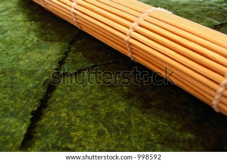 Rolled sushi mat (used for making sushi) laying on sheets of nori (seaweed).