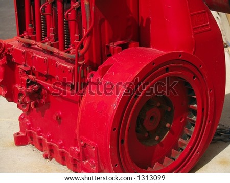 Bright red painted industrial engine with flywheel and valve springs showing.
