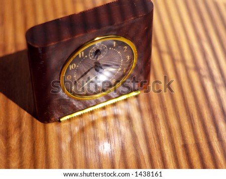 Wear-worn antique clock in strong light and shadow cast by sun filtering through window blinds.