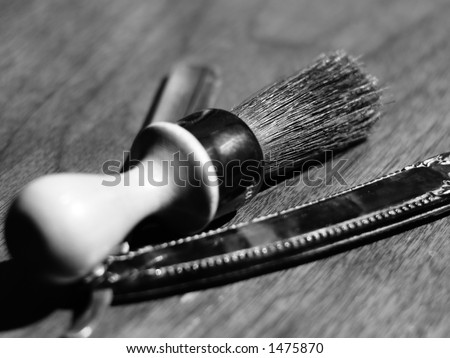 Black and white view of shaving brush and vintage sharpened shaving blade for men.
