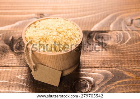 Uncooked rice in a bowl on a dark wooden table with label
