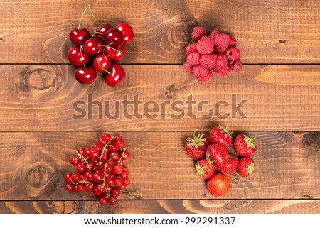 Collection of cherries, strawberries, red currants, raspberries on wood background