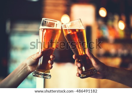 Two friends toasting with glasses of light beer at the pub. Beautiful background of the Oktoberfest. fine grain. Soft focus. Shallow DOF
