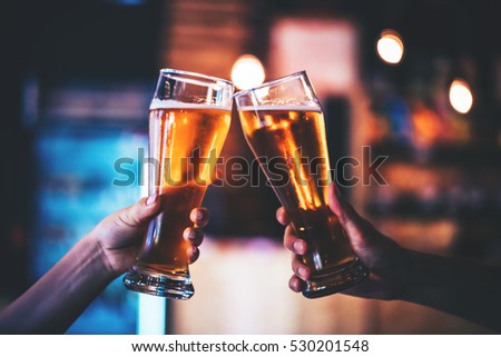 Two friends toasting with glasses of light beer at the pub. Beautiful background of the Oktoberfest. fine grain. Soft focus. Shallow DOF.
