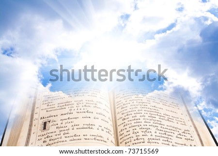 open bible with mystical rays against clouds