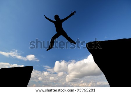 female silhouette jumping from one rock to another in the sky