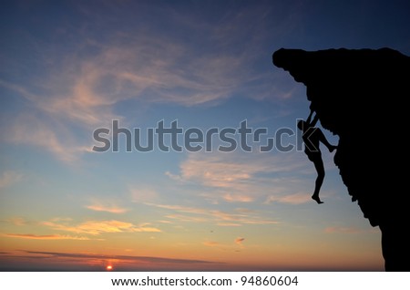 silhouette of a person without insurance climbs the rock in the background of the sunset