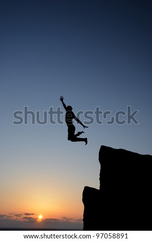 people jumping from the top of the mountain on the background of the sunset