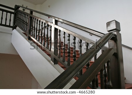 Wooden stairways with dark wood railings white walls