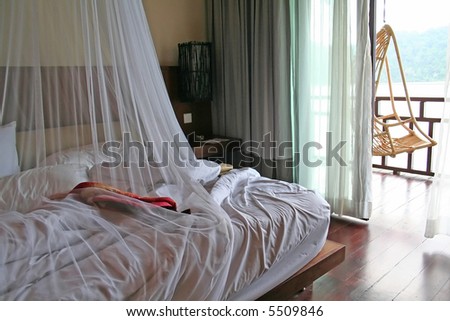 Tropical bed with mosquito netting and balcony