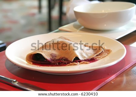 Crepe with jam filling on white plate in restaurant