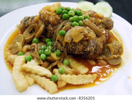 Fried chicken chop in gravy with fries and peas