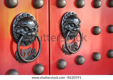 Ornate doorways to traditional chinese temple with guardian door knockers