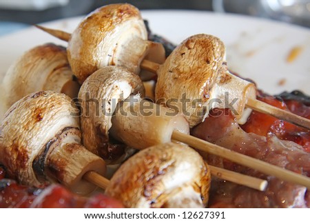 Grilled meat and mushrooms skewered on wooden sticks