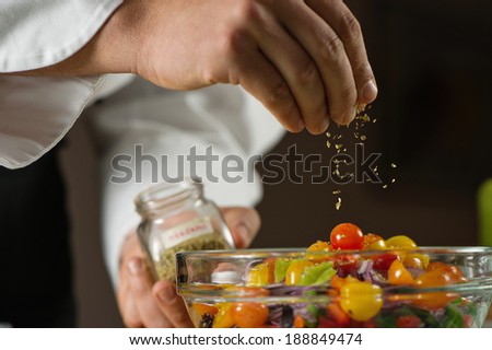 chef making an ecological and raw salad with cheri tomatoes, peppers, onions, olive oil