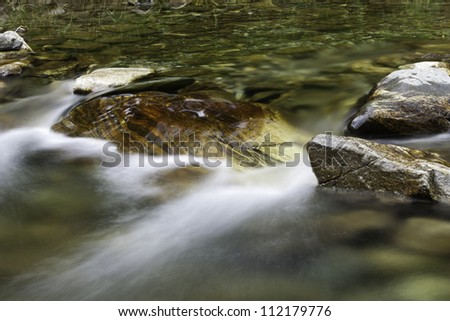 The swift moving water flows along over rocks in this stream.