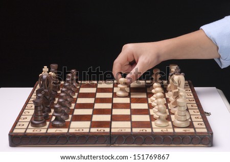 A chess player makes the first move with a pawn on a chess board.