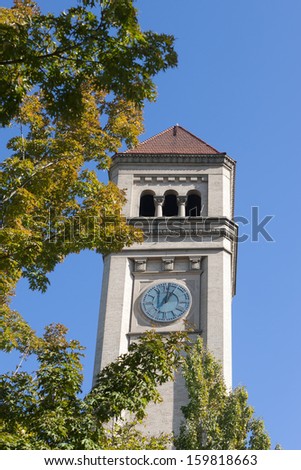 The Clock tower behind tree branches at Spokane, Washington riverfront park.