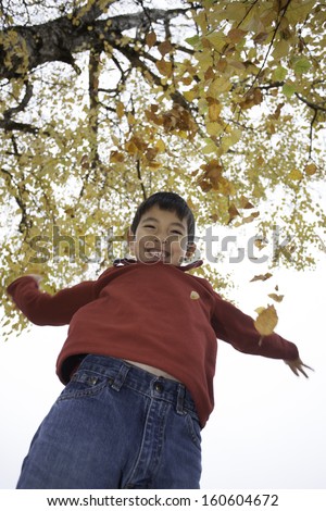 Boy throws leaves up.
