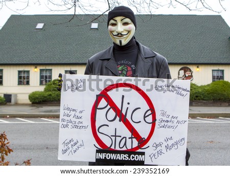 Spokane, Washington USA - December 20, 2014. A protestor in a Guy Fawkes mask displays a sign at a rally in Spokane Valley, Washington.