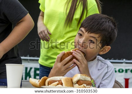 Rathdrum, Idaho USA - August 15, 2015. A young boy participates in a hot dog eating contest during taste of Rathdrum in Idaho USA August 15, 2015.