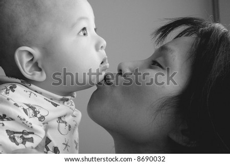 Mother kisses baby son on the chin.