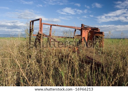 Old farm machinery sits abandoned next tot a farm field.