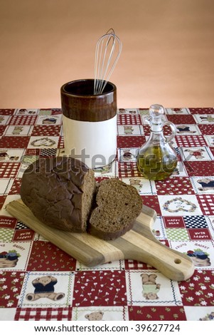 A display of dark bread cutting board with a utensil jar and olive oil cruet.