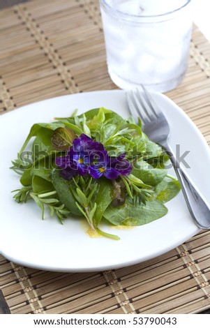 A fresh spinach salad with an edible flower garnish.