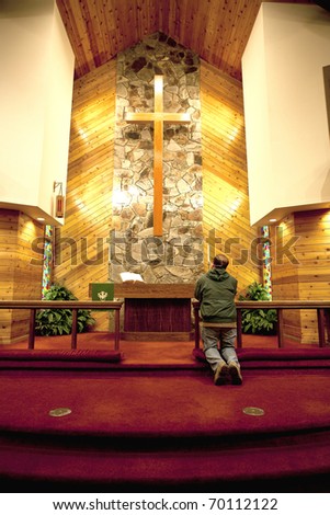 A person is praying alone in a quiet church.