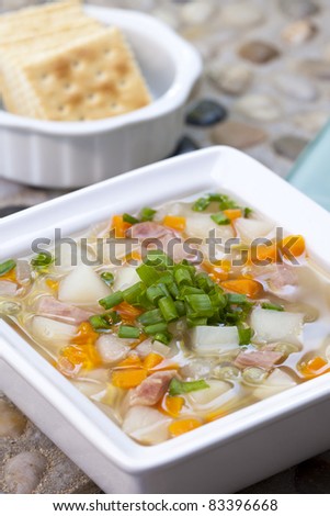A close up of a bowl of homemade soup with crackers.