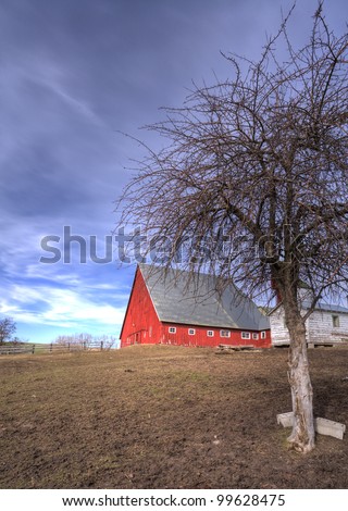 Red barn by a dirt field.