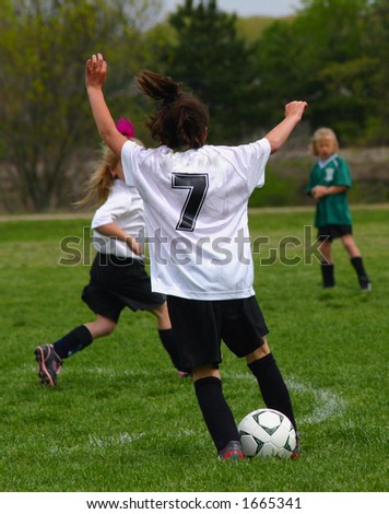 solitary female soccer player arms raised with soccer ball