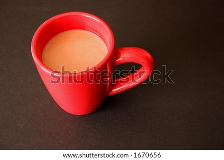 cup of creamed coffee in red mug on black background