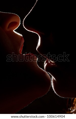 Silhouette of two sexy woman kissing in darkness through light