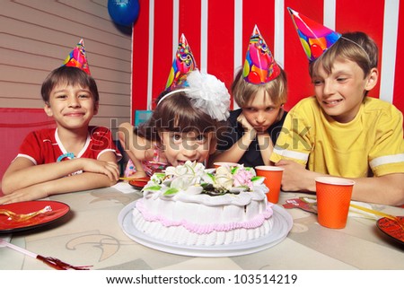 Little girl going to eat cake in her birthday round about her friends
