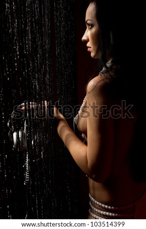 Fashion model with white retro headphones looking through the curtain