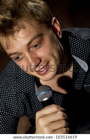 Young handsome guy singing and sitting on floor