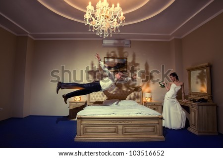 Happy groom flying on bed to his sweetheart in a stylish bed