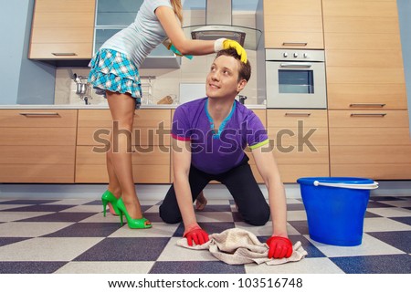 Young man cleaning floor and looking at her girlfriend