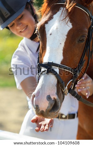 Portrait of  female jockey feeding purebred horse