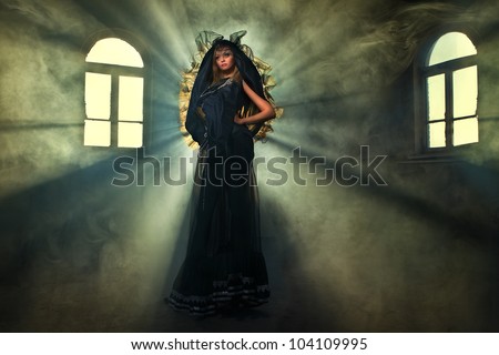 Sexy witch dressed up in black dress covered in smoke