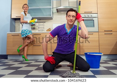 Young man cleaning floor with his girlfriend at kitchen
