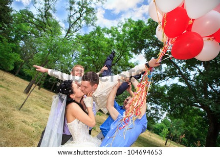 Bride kissing her happy groom tossed into sky by friends